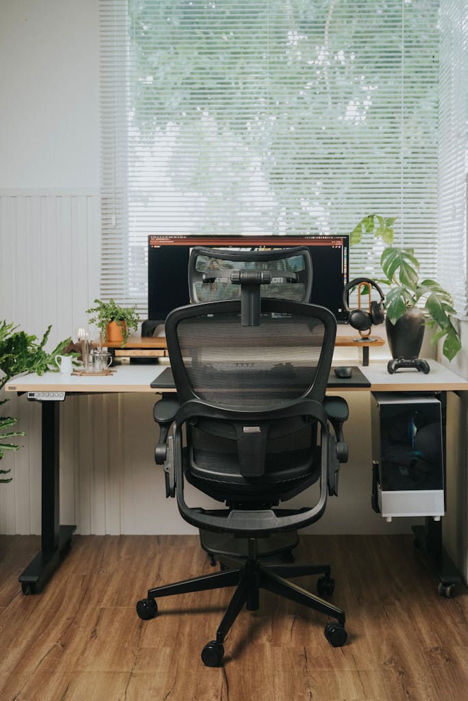 A minimalist home office setup featuring a sleek ergonomic chair, desk, and monitor.