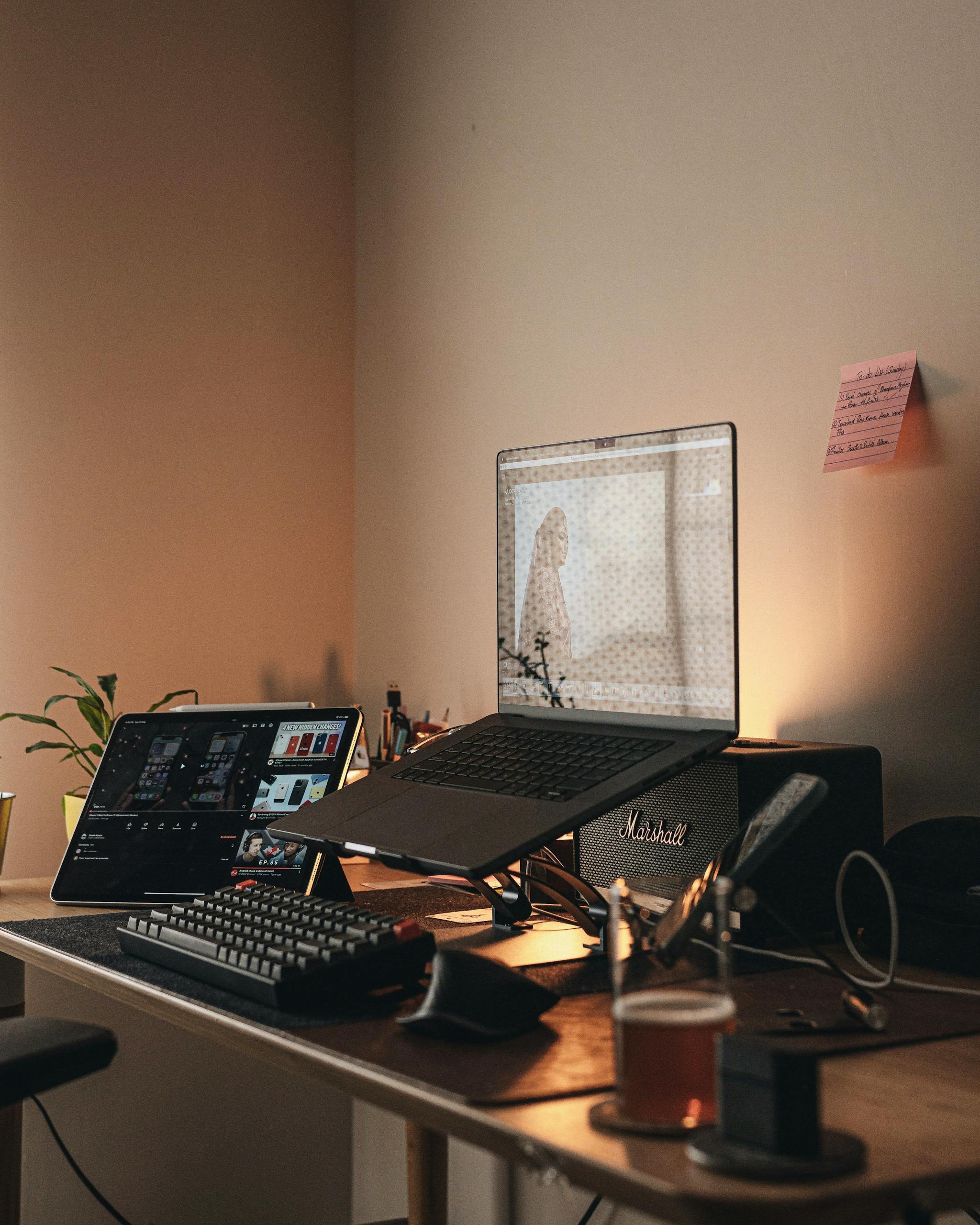 A warm, minimalist home office setup featuring a laptop, keyboard, and ambient lighting.