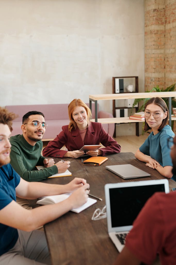 Engaged team of young adults collaborating in a modern office setting, promoting teamwork and idea sharing.